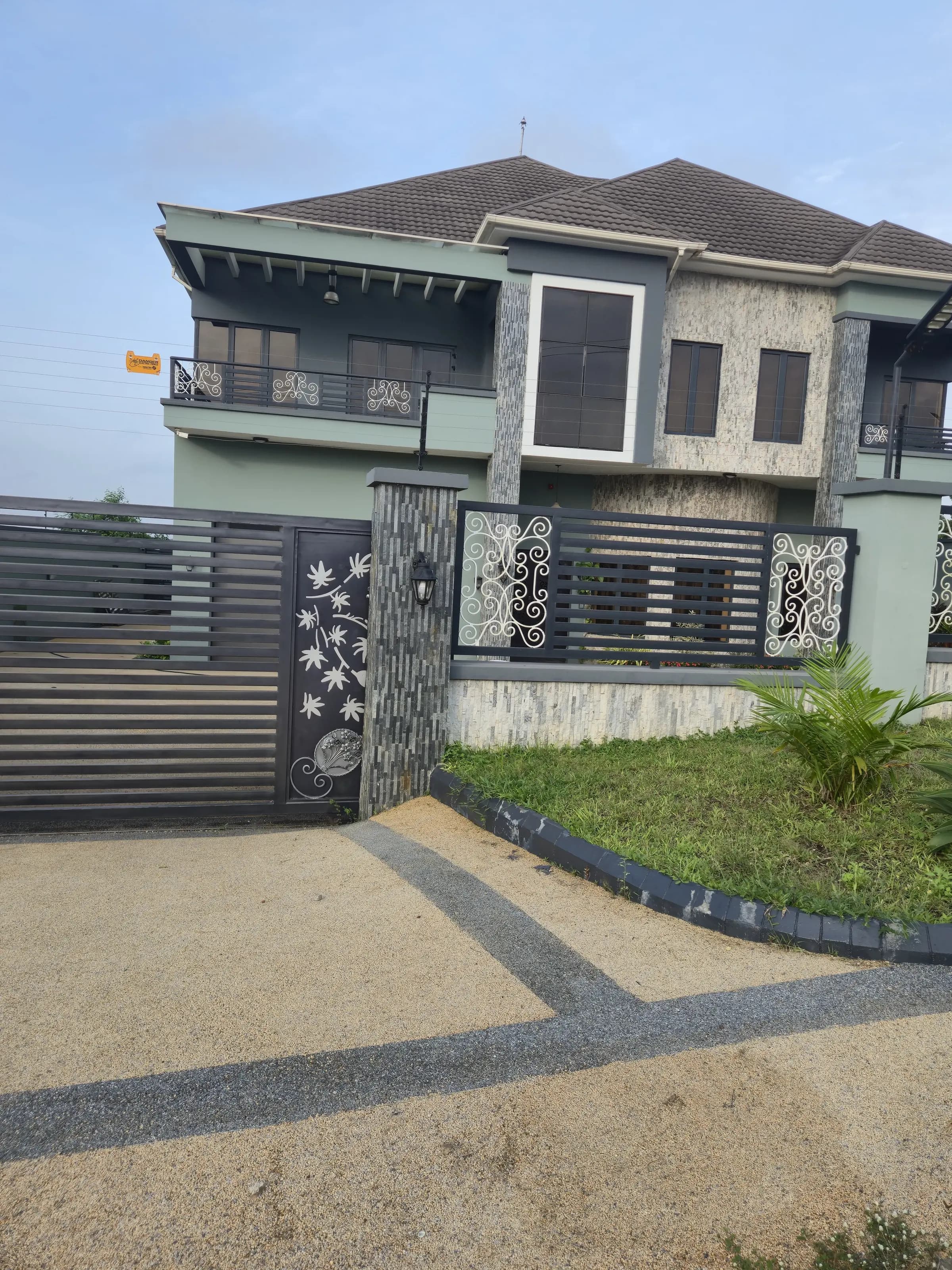 Completed Abeokuta residence with wrought-iron gate, stone-clad pillar and upper balcony