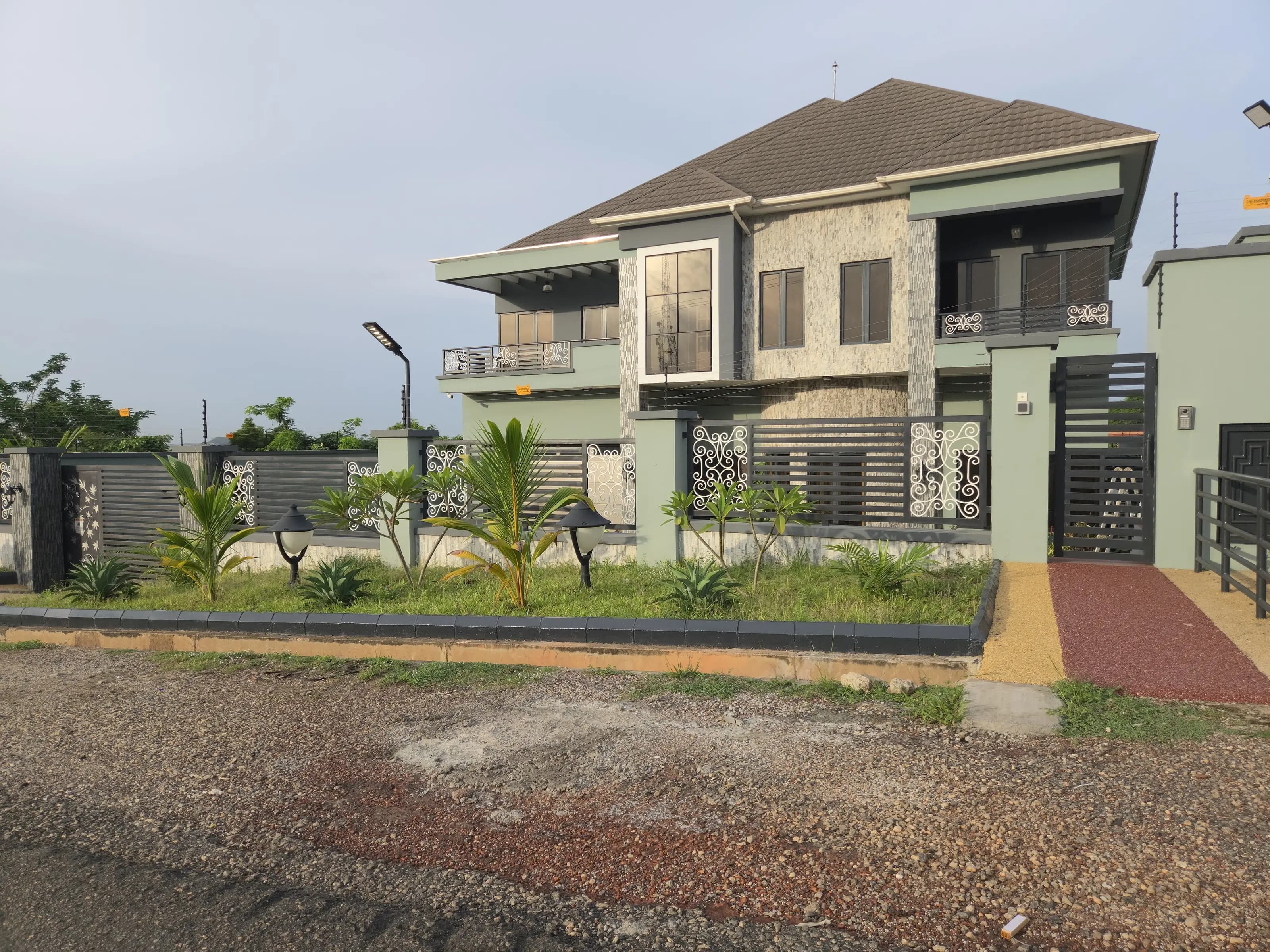 Completed two-storey Abeokuta residence at dusk, showing the stone-clad facade and entrance gate