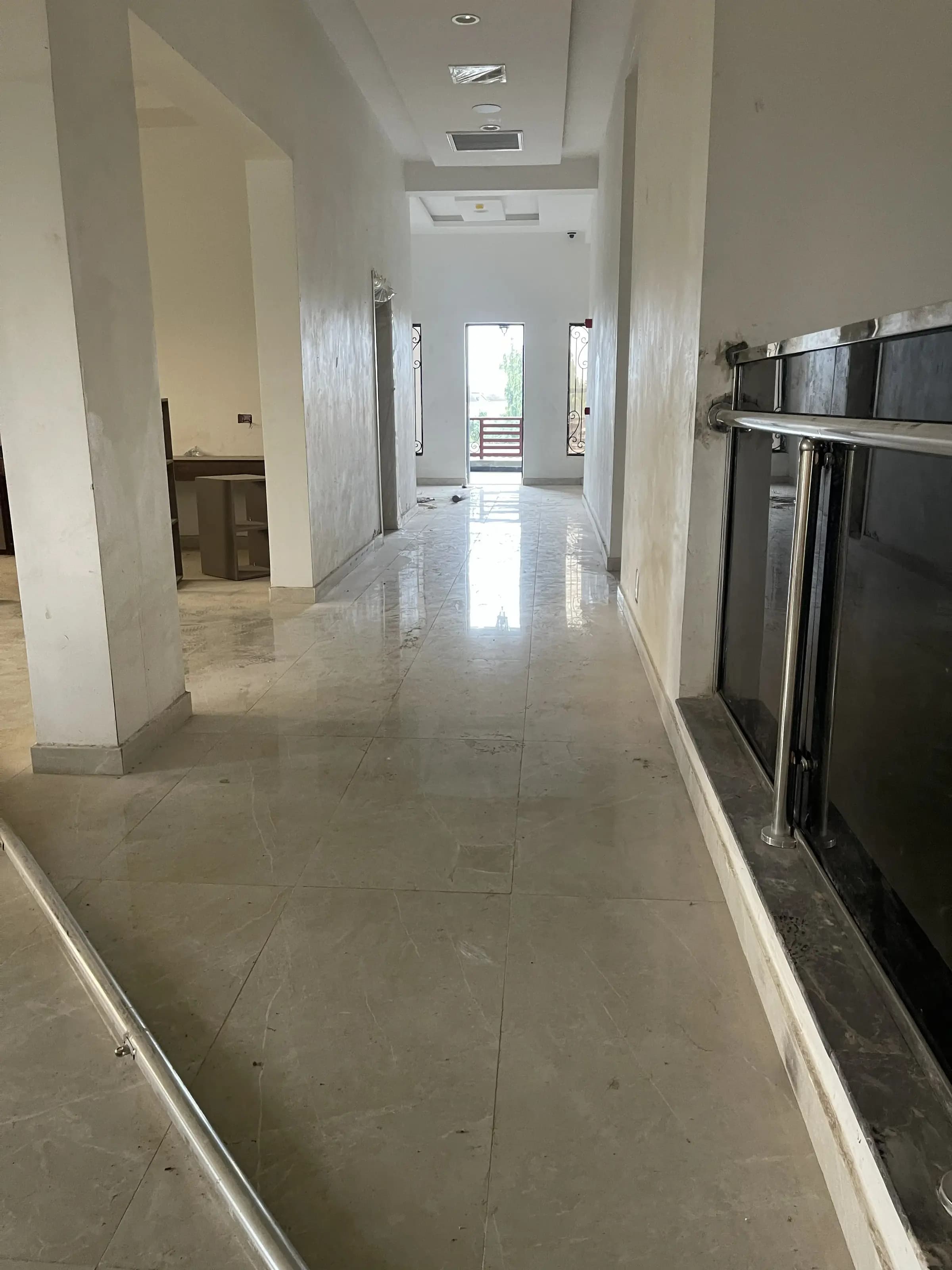 Interior hallway of the Abeokuta residence with marble flooring and glass balustrade