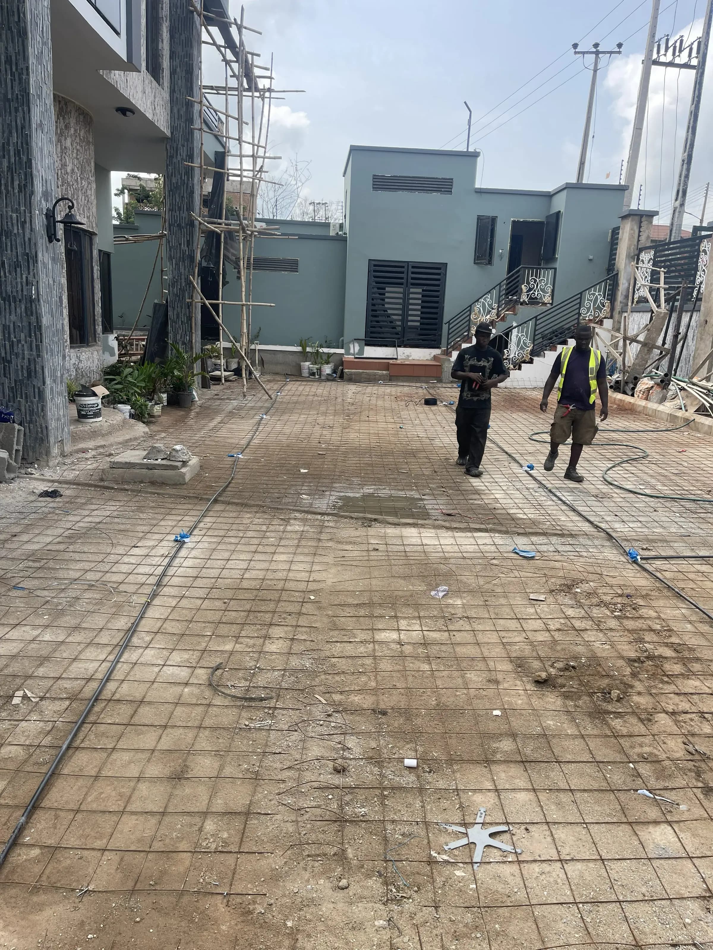 Reinforcement mesh laid across the Abeokuta courtyard ahead of concrete pour, site team at work
