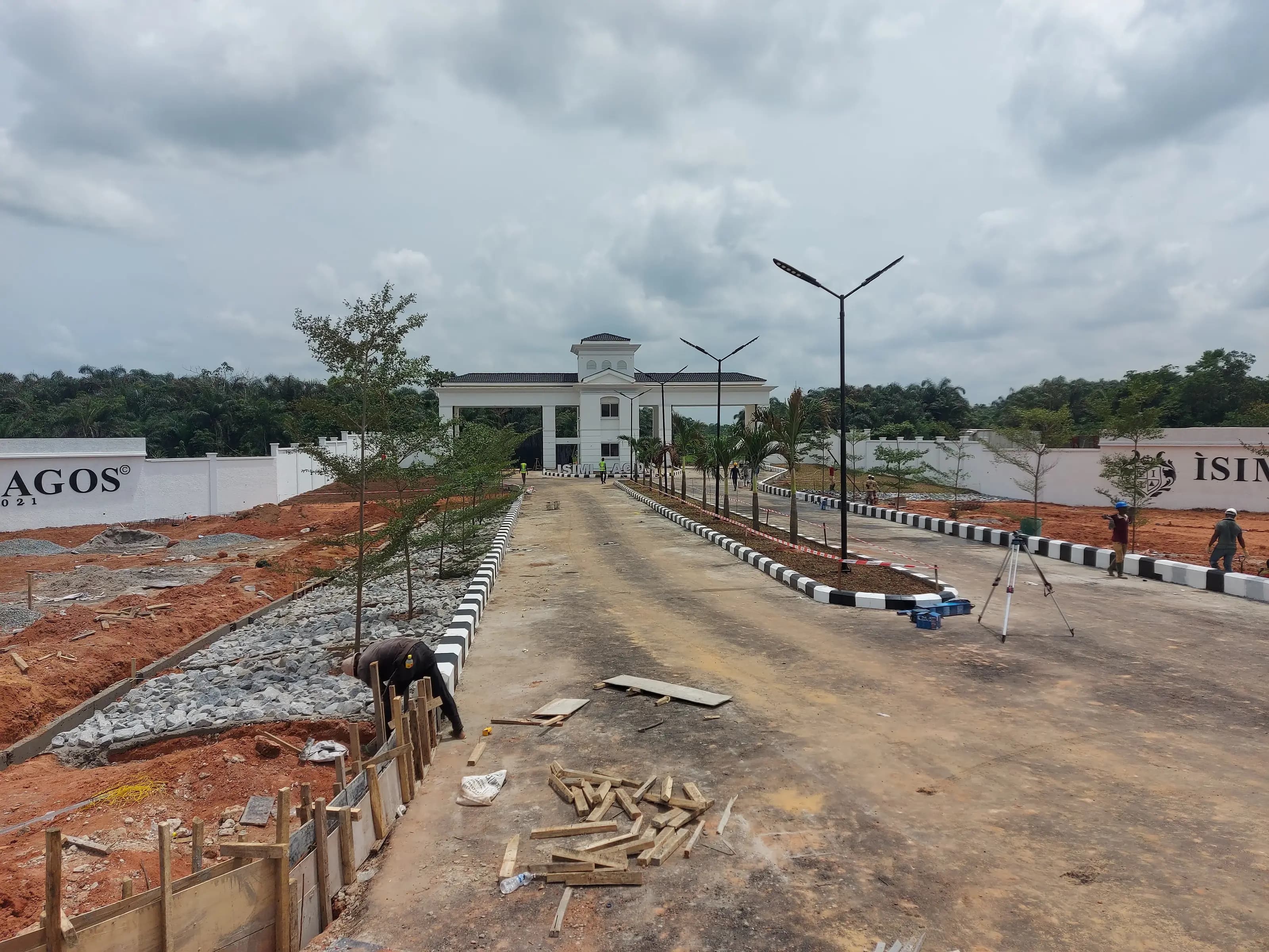 Isimi Lagos estate entrance road under construction, with the gatehouse and estate wall signage in view