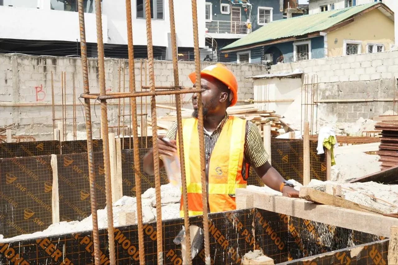 Engineer supervising reinforced concrete formwork pour, wearing a branded site vest